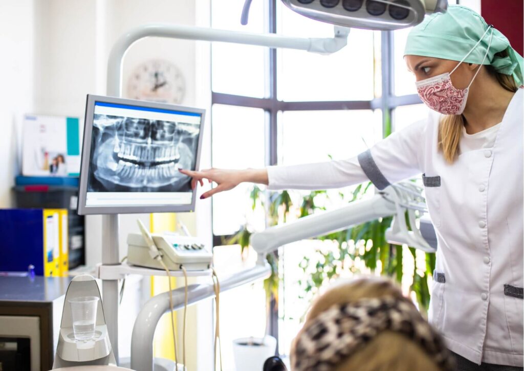 Dentist reviewing a panoramic dental X-ray to evaluate wisdom tooth eruption and determine if removal is needed.
