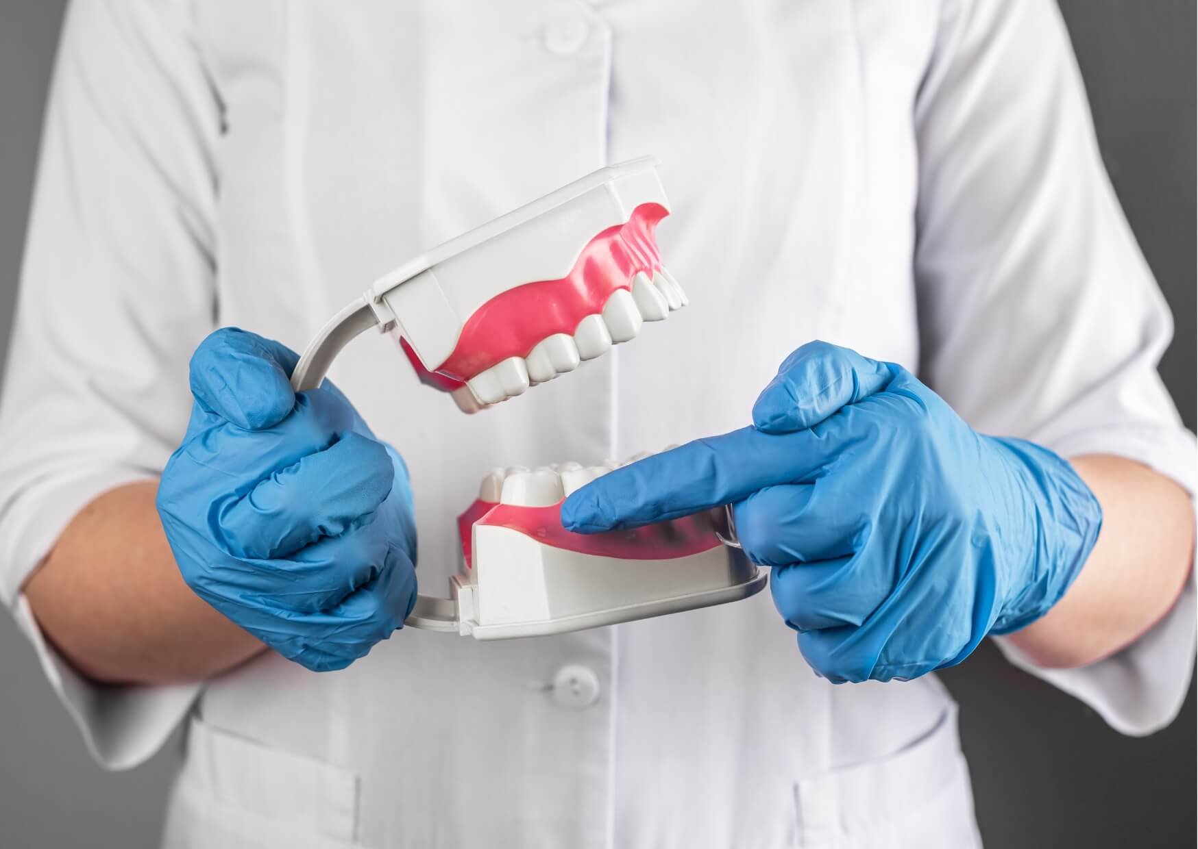 Dentist using a dental model to explain how wisdom teeth come in and affect surrounding teeth.