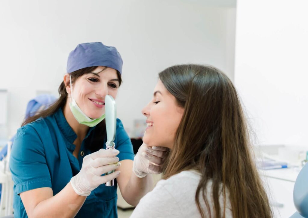Dentist showing a patient her smile during a follow-up visit to monitor progress after gingivitis treatment.