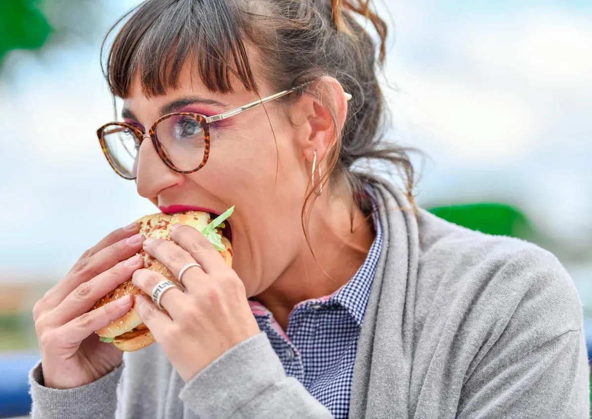 Woman eating a burger after recovering from wisdom teeth removal.